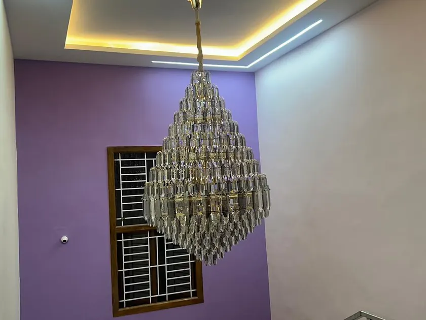 Bedroom with a lilac feature wall, cove lighting and a beaded chandelier