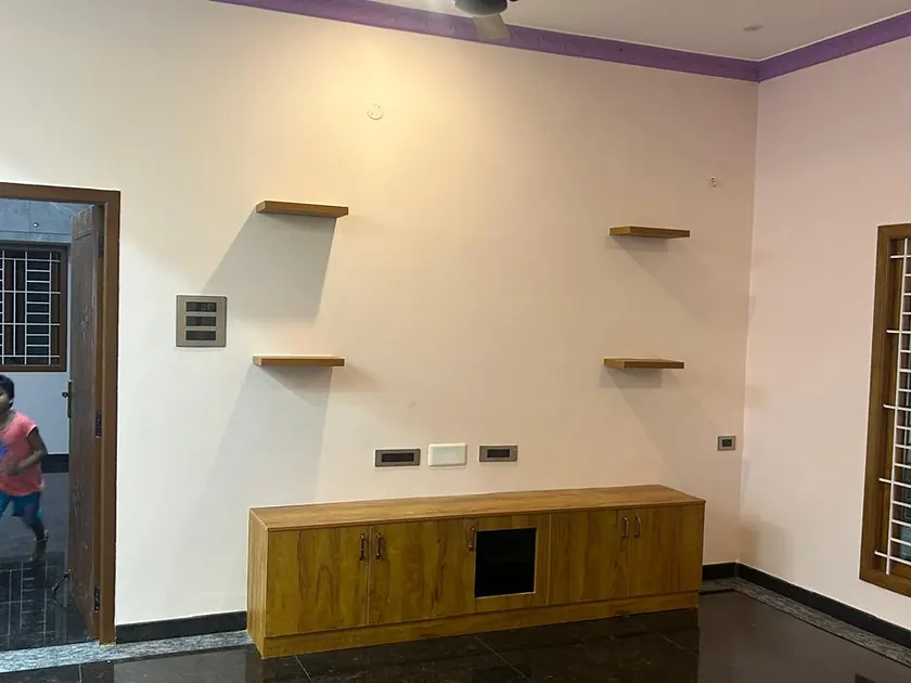 Living space with low timber console, wall shelving and polished floor