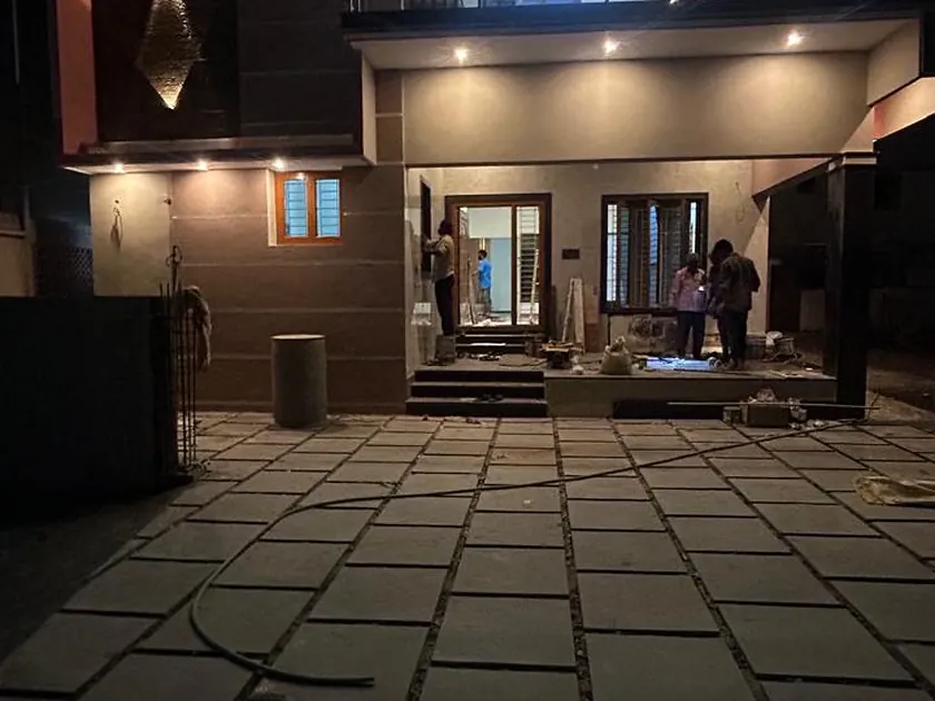 Covered entrance and paved forecourt of a completed residence, lit at night