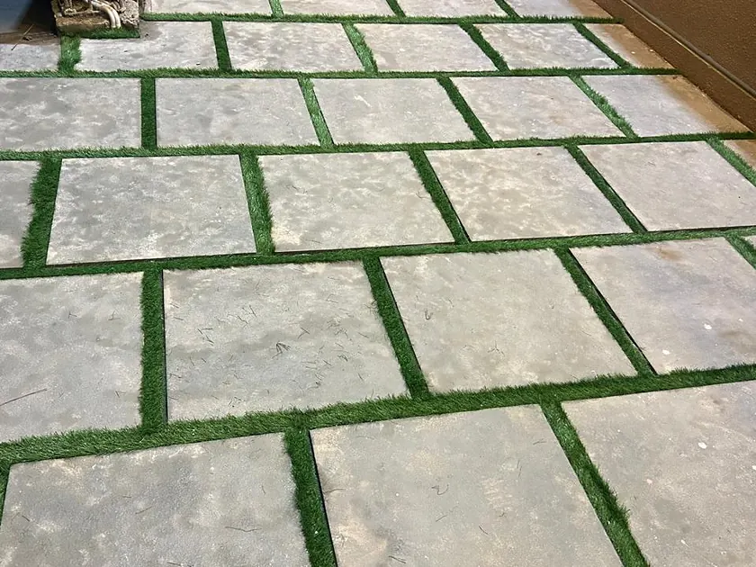 Large-format stone paving with grass joints across a finished courtyard