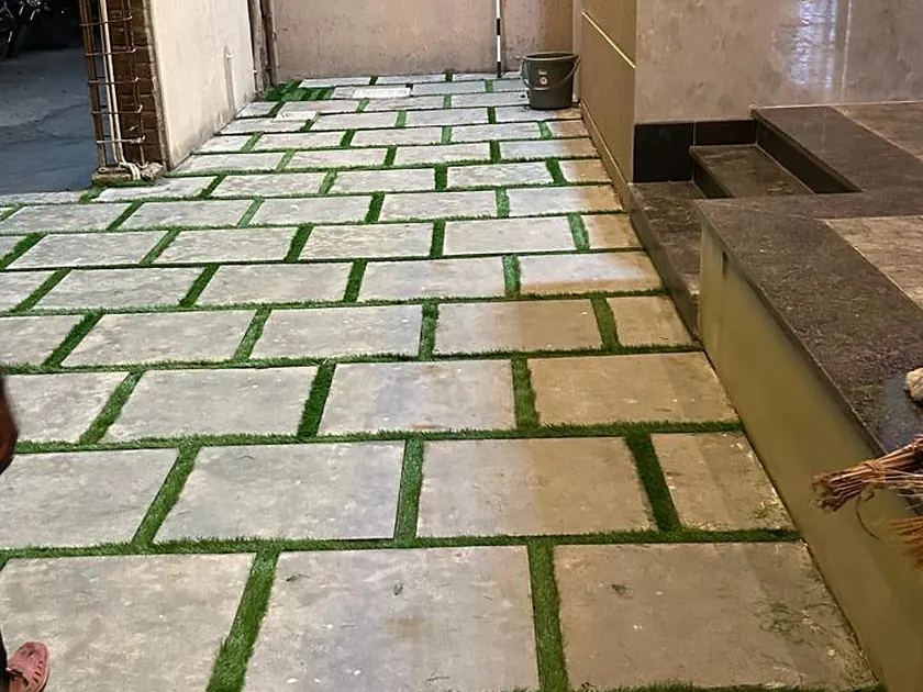 Stone paving slabs laid with planted grass joints alongside a boundary wall